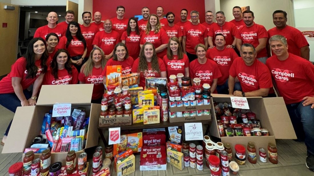 Employees pose with boxes of donated food