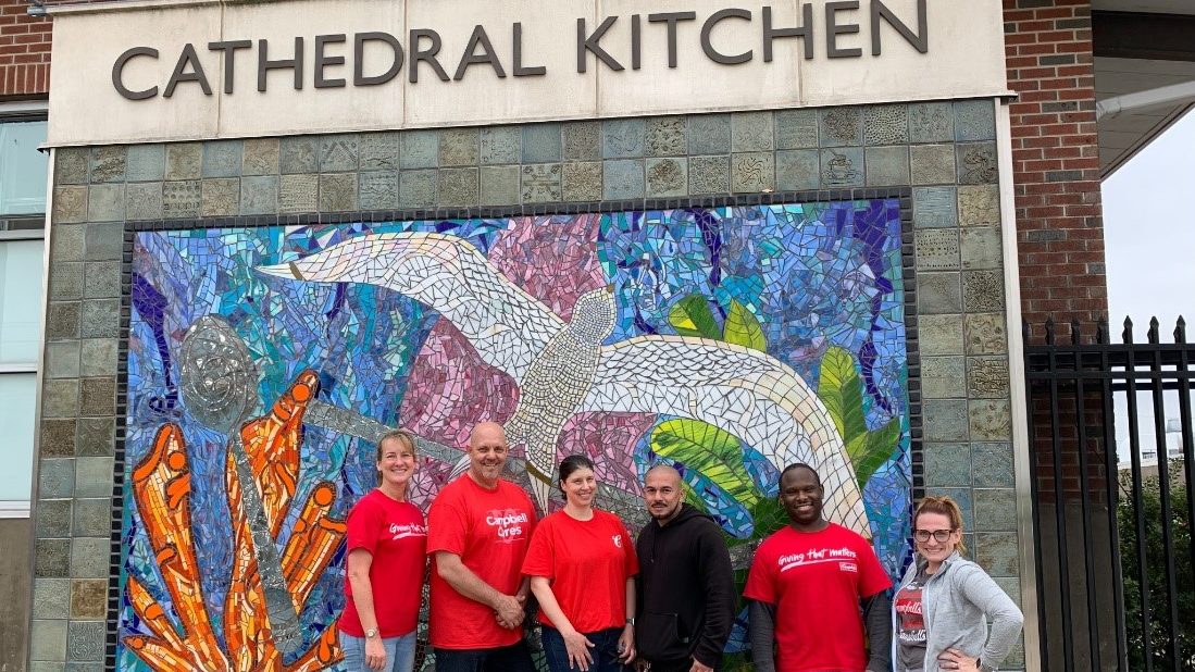 Employees pose outside Cathedral Kitchen sign