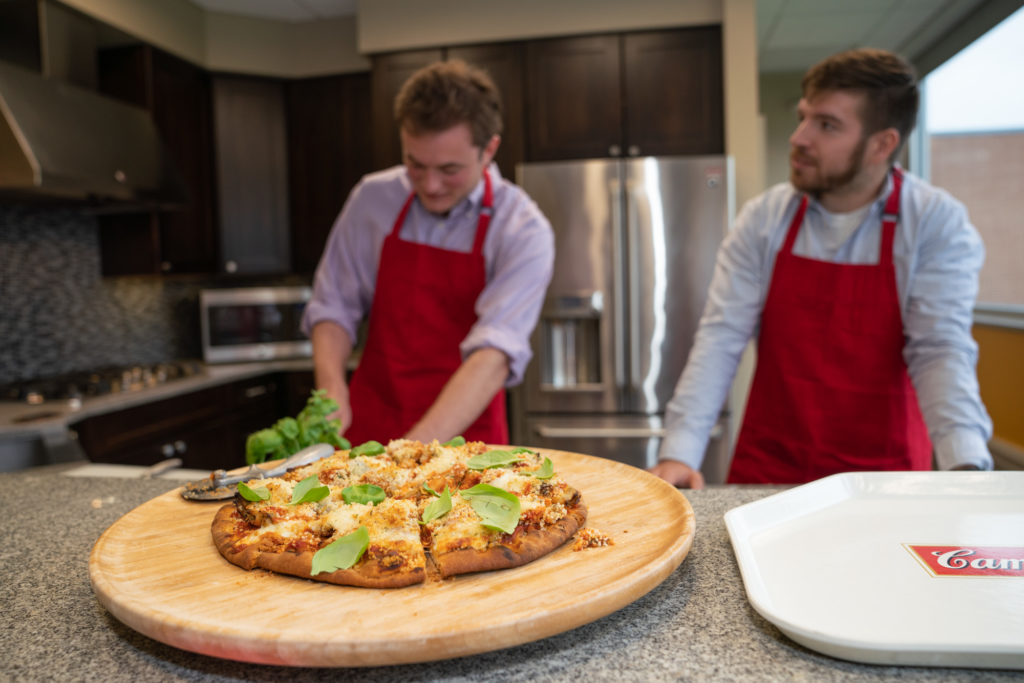 two interns making pizza in kitchen