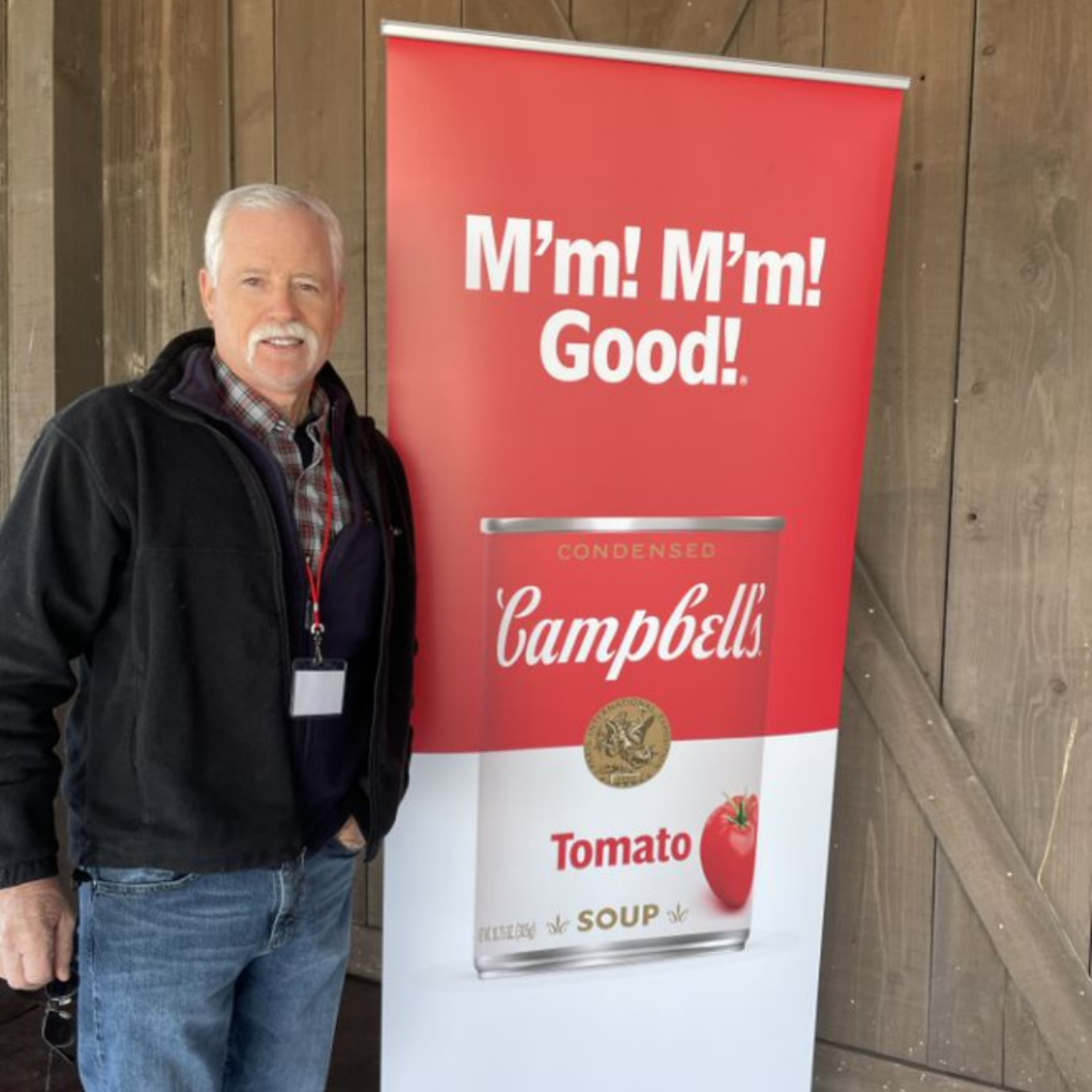 Bruce Rominger poses by Campbell Tomato soup sign